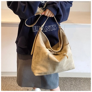 Gros plan du sac bandoulière en daim beige avec nœud coulissant et large sangle
