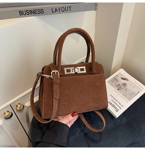 Detailed close-up of dark brown suede handbag with silver metal twist lock on a seat