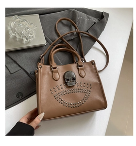 Gros plan d'un sac cabas en cuir caramel avec rivets et boucle tête de mort métallique