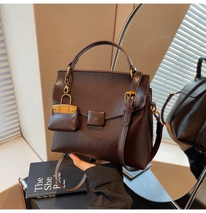 Detail of dark brown retro square handbag with metallic lock charm and leather handle
