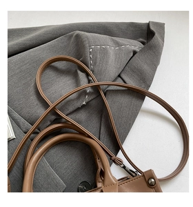 Gros plan détaillé du sac cabas en cuir marron foncé avec surpiqûres blanches et bandoulière fine
