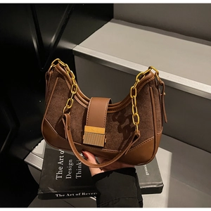 Close-up of retro hobo bag with contrast stitching, gold chain, and metal bar lock