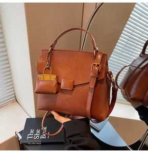 Detail view of brown vintage square bag with adjustable strap and mini bag charm