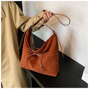 Détail du sac hobo en suédine caramel avec surpiqûres blanches et nœud décoratif élégant