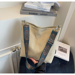 Detail of beige canvas bucket bag with bohemian printed wide shoulder strap and metal hooks