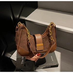 Detail of a brown leather and suede saddle bag with a golden square buckle and chain strap