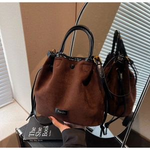 Détail du sac seau en daim marron avec fermeture à cordon et poignée en cuir noir