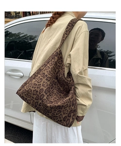 Detail showing the large leopard print tote bag draped on shoulder in outdoor light
