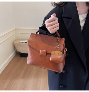 Close-up of vintage brown leather handbag featuring a mini charm and gold hardware