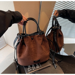 Détail du sac seau rétro en daim marron avec cordon et poignée en cuir noir brillant