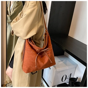 Détail d'un cabas en daim caramel avec surpiqûres blanches et nœud décoratif