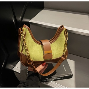 Detail of green suede crescent bag with brown leather trim and golden chain strap