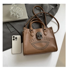Détail du sac en cuir marron avec boucle tête de mort, clous et bandoulière amovible