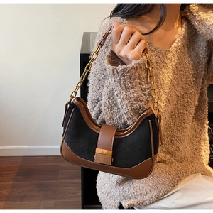 Detail of vintage contrast shoulder bag with gold chain strap on a brown sweater