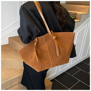 Détail du sac cabas en daim marron caramel avec nœuds élégants et texture mate
