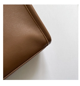 Gros plan sur la texture du cuir marron et les coutures détaillées d'un sac cabas