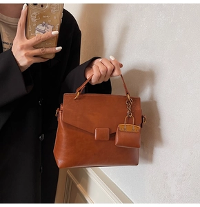 Detail of vintage brown leather handbag with matching charm and bronze hardware finish
