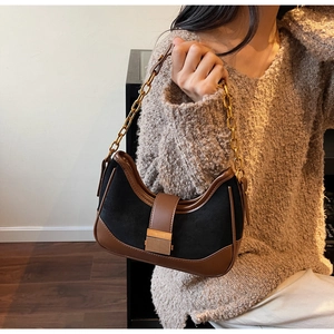 Detail of a retro hobo bag with black suede patchwork and a gold chain shoulder strap