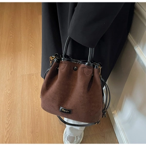Détails de texture du sac seau en daim marron foncé avec cordon et logo doré