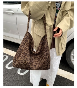 Outdoor street style view of a large leopard print tote bag carried by a model on the shoulder