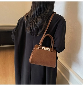 Close-up of a dark brown suede tote bag with golden metal buckle and dual handles