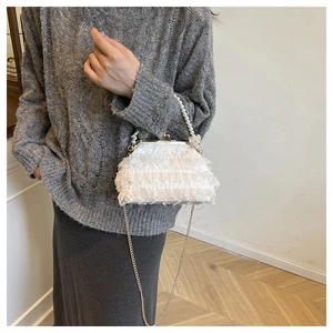 Détail du sac de soirée en dentelle blanche avec anse perle et bandoulière dorée