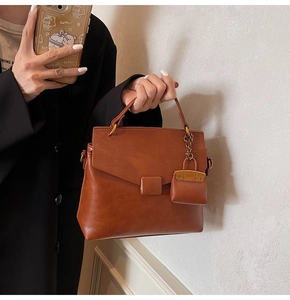 Detail of a brown vintage leather handbag with matching square buckle and mini charm