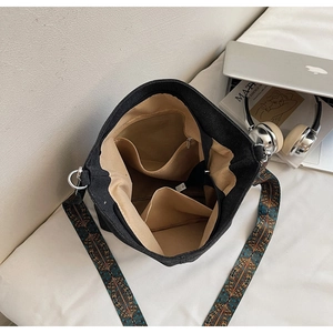 Detail view of spacious black bucket bag interior with organized pockets and woven strap