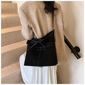 Détail du sac cabas en suédine noire avec surpiqûres blanches et détail de nœud élégant
