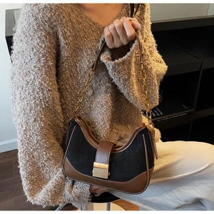 Close-up of hobo bag featuring black suede material and brown leather trim detailing