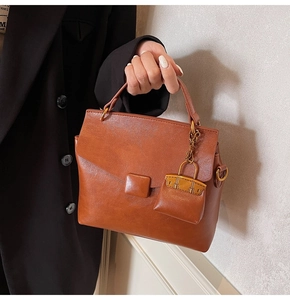 Detail of vintage brown leather handbag with mini charm and metal buckle on black blazer