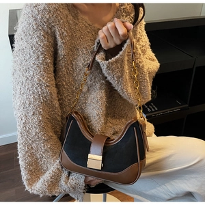Detail of retro contrast shoulder bag with black suede texture and brown leather trim