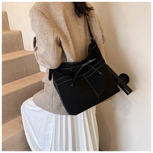 Détail du sac cabas en daim noir avec coutures contrastées et nœud décoratif élégant