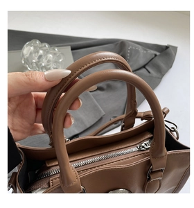 Détail du sac cabas en cuir marron avec doubles poignées et fermeture éclair métallique