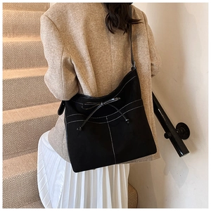 Détail d'un sac à bandoulière vintage noir avec coutures blanches et nœud décoratif