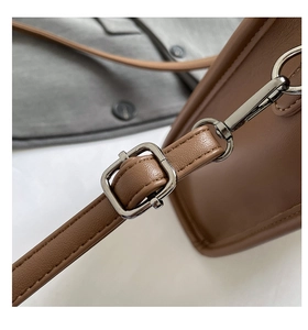 Détail de la bandoulière en cuir réglable et boucle en métal argenté du sac marron
