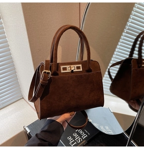 Detail view of coffee brown suede tote bag featuring premium gold hardware and dual handles