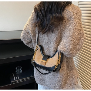 Detail view of a vintage patchwork underarm bag with gold chain and buckle on a model