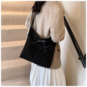 Détail du grand sac cabas noir en daim avec surpiqûres blanches et nœud décoratif