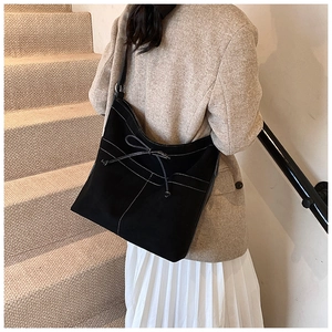 Détail du sac cabas en suédine noire avec surpiqûres blanches et nœud décoratif