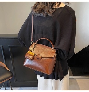 Detail view of a vintage dark brown leather crossbody bag with a chain accessory