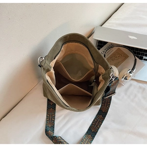Interior view of army green canvas bucket bag showing zipper pocket and printed strap