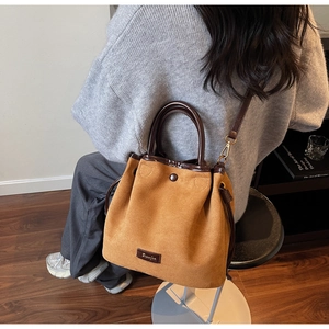 Vue détaillée du sac seau en daim camel avec bordures et poignée en cuir marron contrasté