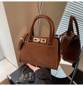 Close-up of vintage brown suede handbag with golden metal twist lock and light shadows
