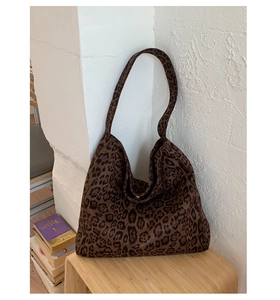 Detail of a large leopard print tote bag against a minimalist white textured wall