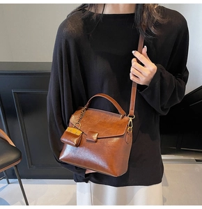 Detail shot of vintage brown PU leather handbag featuring a mini pouch charm and flap closure