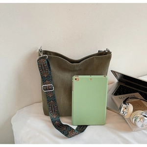 Detailed view of olive green canvas bucket bag with colorful bohemian wide strap and accessories