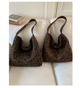 Close-up of leopard print tote bag with thick shoulder strap on a cozy sofa