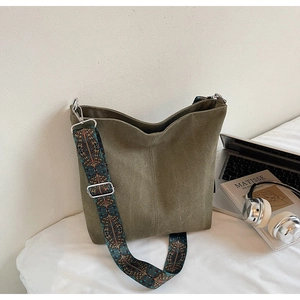 Detail view of army green suede bucket bag with bohemian patterned wide shoulder strap