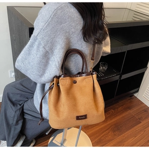 Sac seau en suédine marron avec garniture en cuir porté en bandoulière sur un mannequin